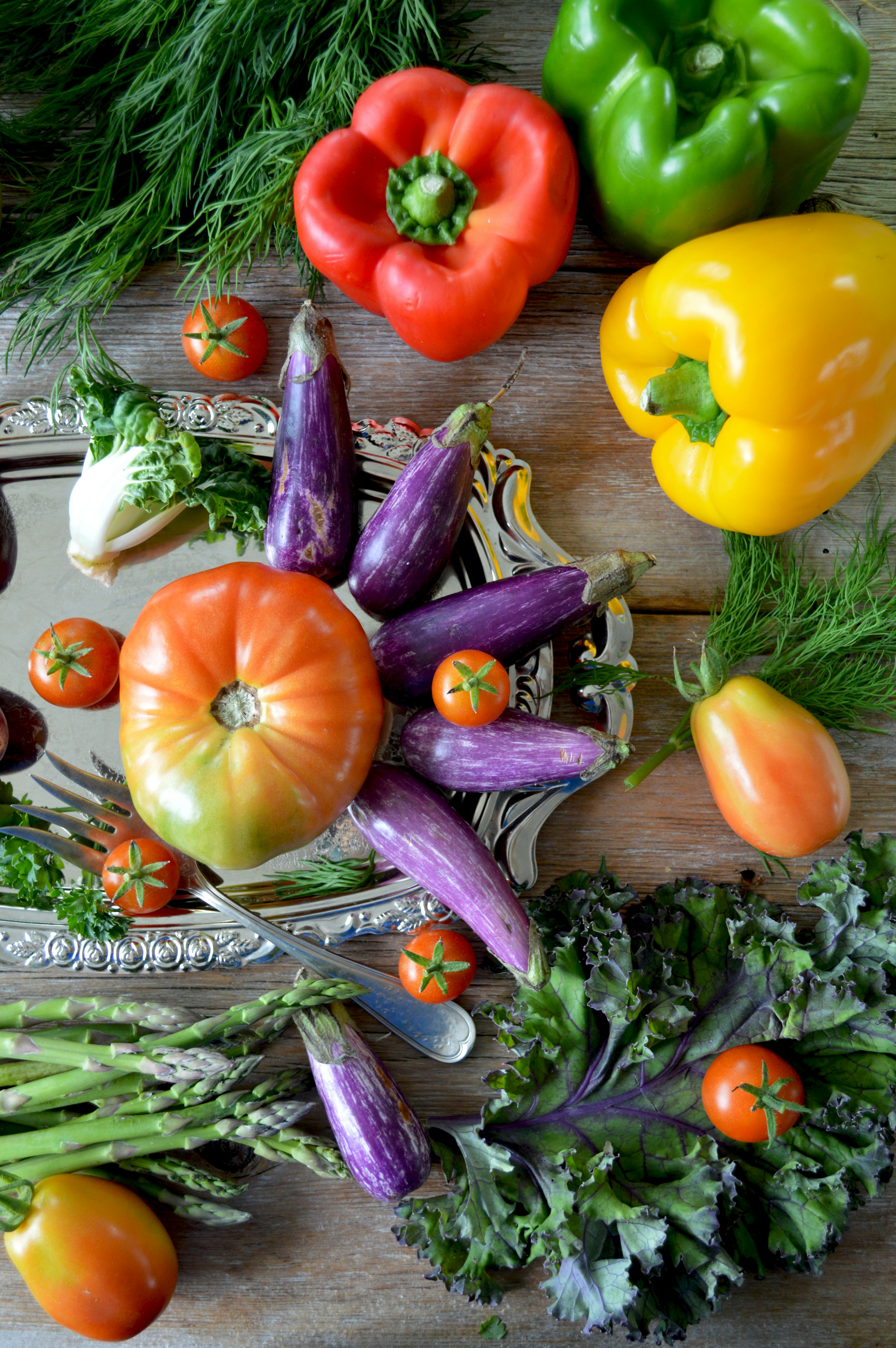 An assortment of fresh vegetables and herbs on a wooden surface